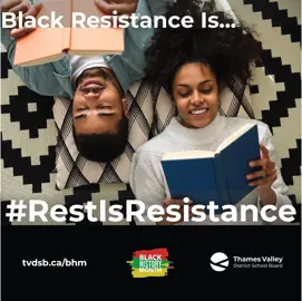 Two Black students relaxing on a patterned rug and smiling while reading books.
