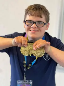 Andrew (AJ) Manning holding medals from the Special Olympics Ontario provincial qualifiers.