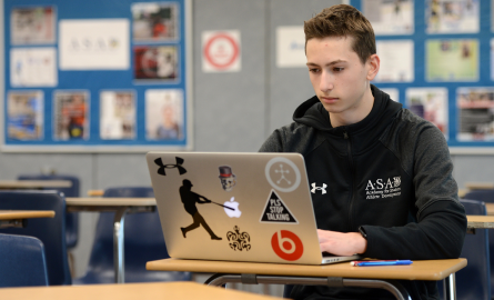 Student studying in a classroom with a laptop