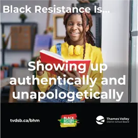 A Black student smiles while holding a book with a pair of headphones around their neck.